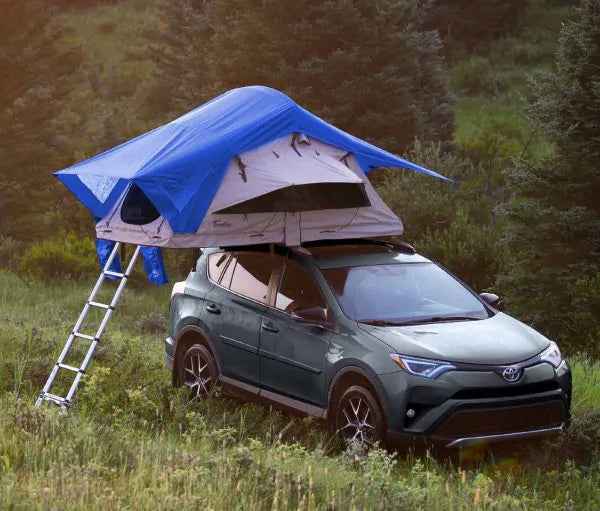 Blue rooftop tent on SUV in wooded outdoor setting