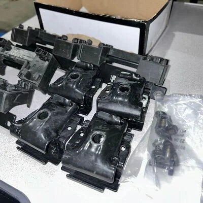 Set of black metal brackets on a gray surface with a cardboard box in the background.