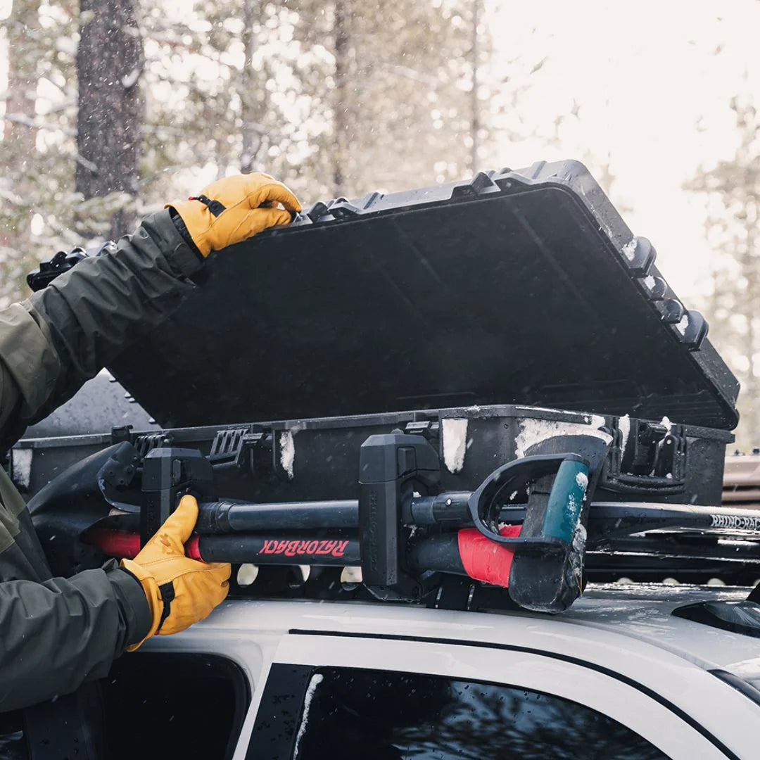 Outdoor user opening Rhino-Rack Cargo Case filled with tools and gear.
