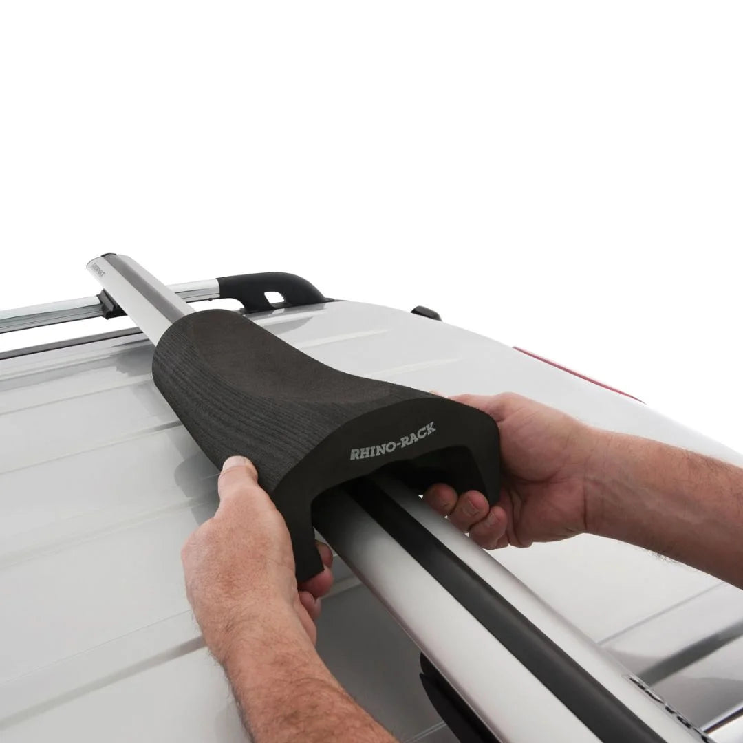 Person installing Rhino-Rack Vortex Foam Wrap Pad onto vehicle crossbar.