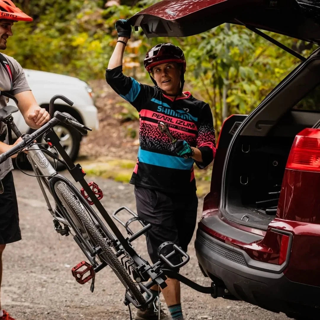 Swagman XTC2 Tilt is fixed to the back of a car. bicycle is on it. both folds back as women opens the trunk of the car