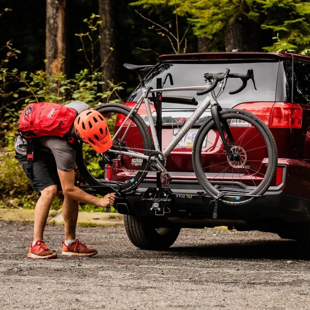 Person attaching bicycle to Swagman XTC2 Tilt at the back of a red car.