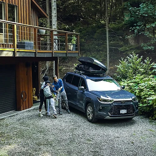 Family packing SUV with Thule Force 3 M rooftop cargo box outside forest cabin