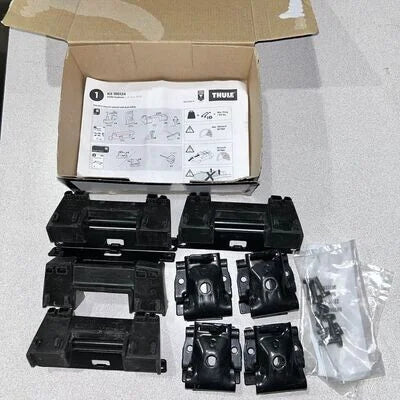 Black mechanical parts and a cardboard box with instructions on a gray surface