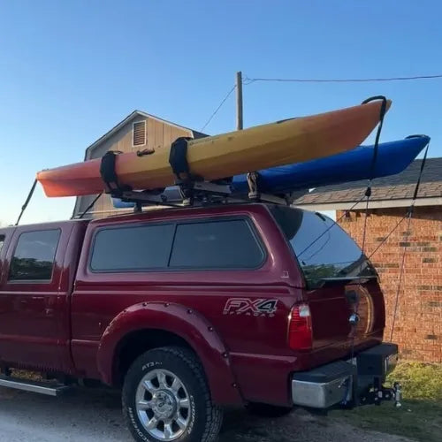 Thule Hullavator Pro Red truck with kayaks on a roof rack against a clear blue sky.