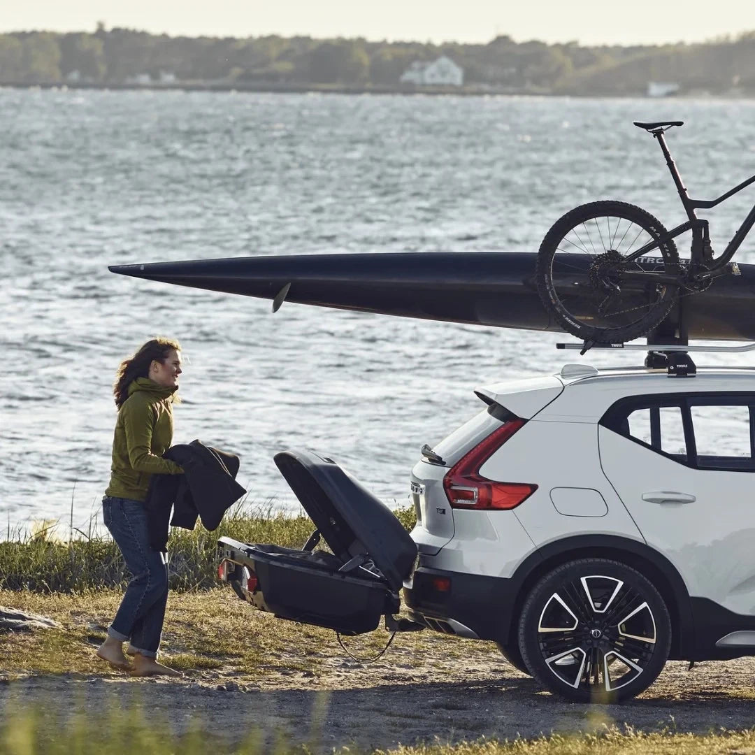 Thule Arcos Box & Platform Bundle installed on white car. Women unloading it
