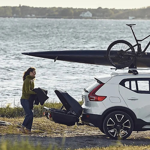 White SUV with kayak and bike on roof, Thule Arcos cargo box on hitch – versatile storage solution keeping roof free for sports gear