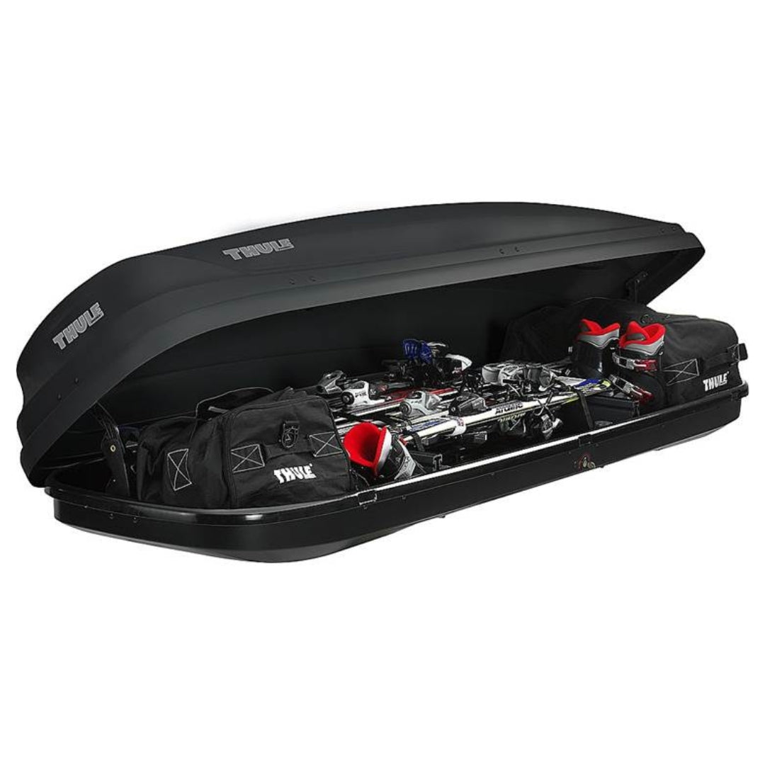Thule Ascent cargo box open to reveal neatly packed gear inside, including ski boots and pole