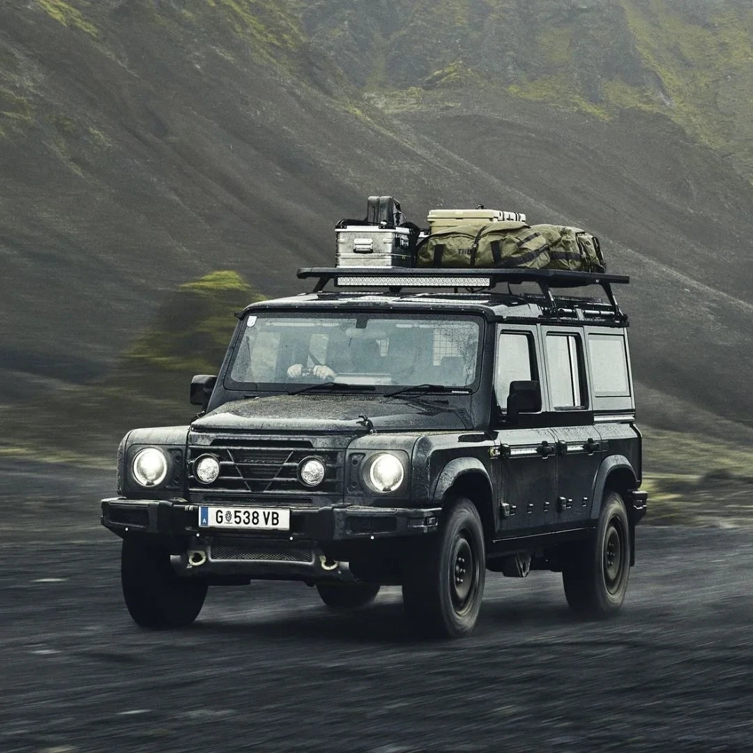Land Rover with rooftop Caprock Platform carrying gear while driving through rugged terrain.