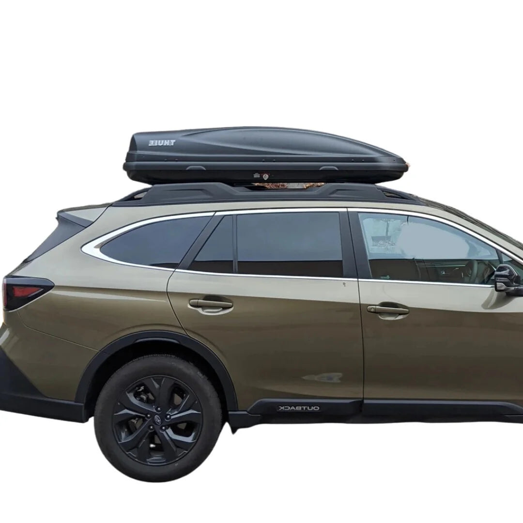 Side view of a brown SUV equipped with a Thule Convoy XT Alpine cargo box parked on pavement.