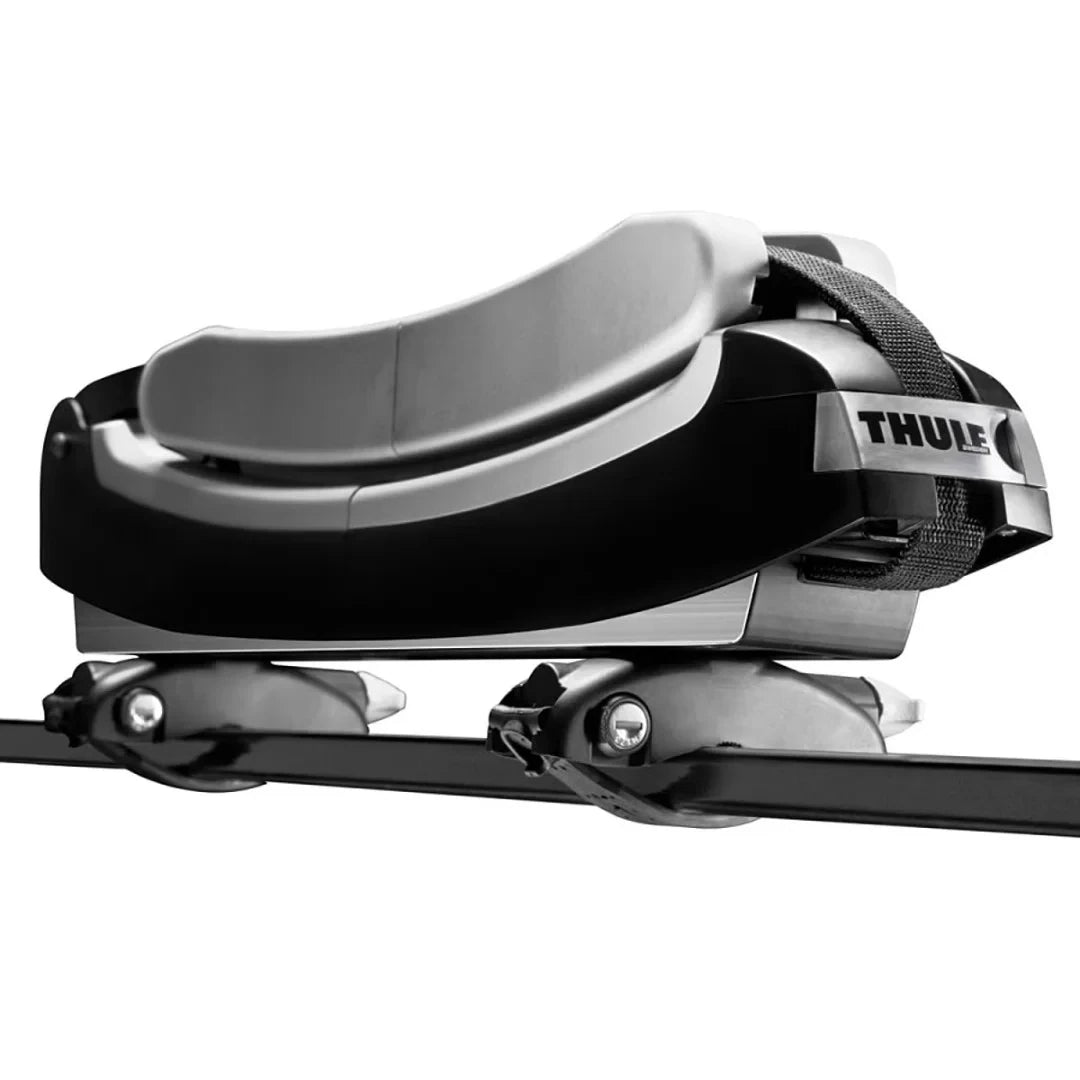 Close-up of Thule surfboard carrier showing padded cradle and securing strap mounted on a roof rack