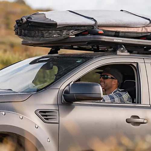 Adventure truck vehicle driving with Yakima SkyLine Tower system supporting rooftop tent and gear