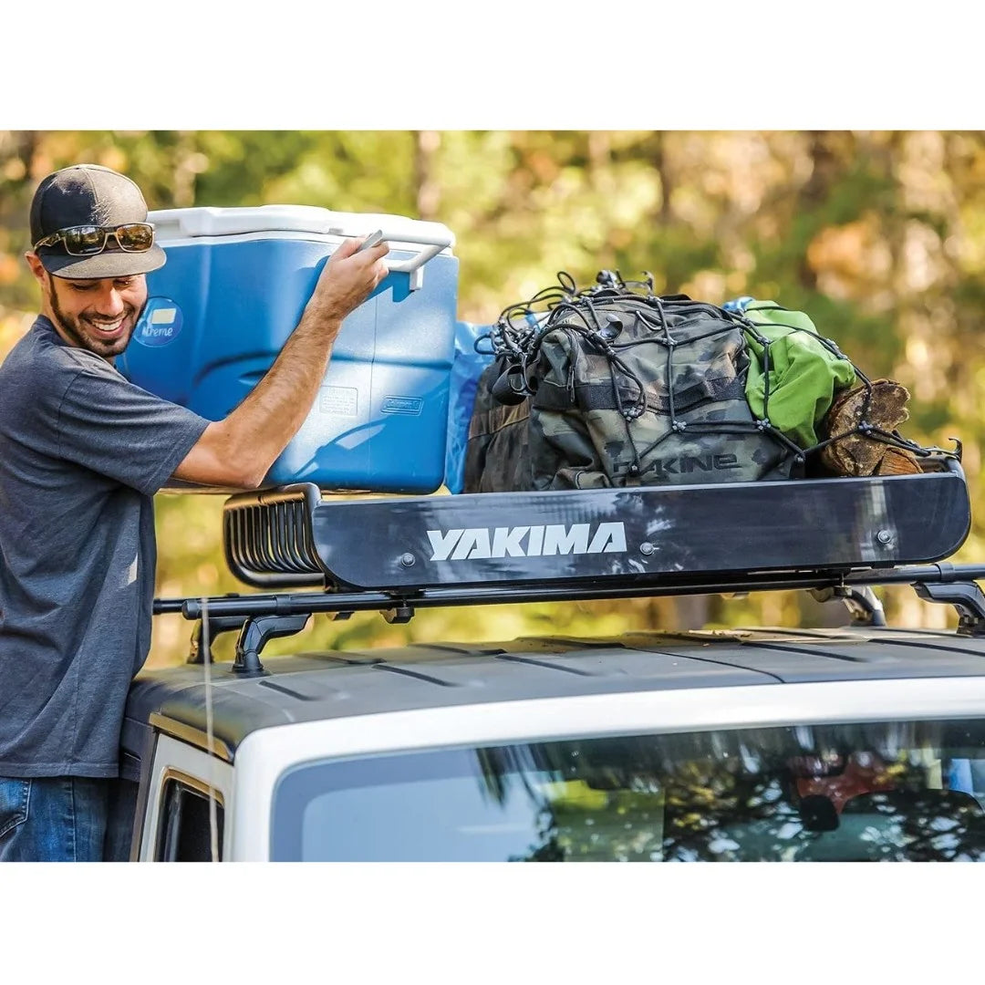 Person organizing gear into a Yakima basket mounted on a car roof.