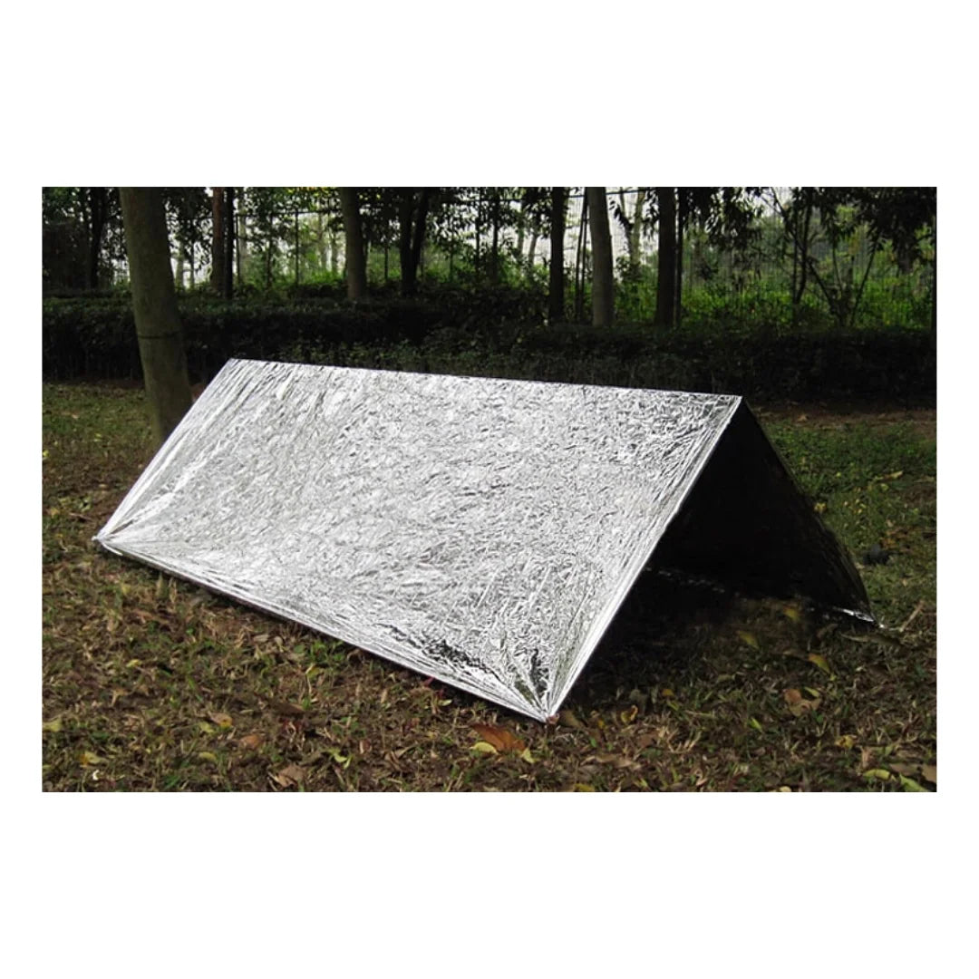 Emergency thermal blanket set up as a reflective survival shelter in a forest