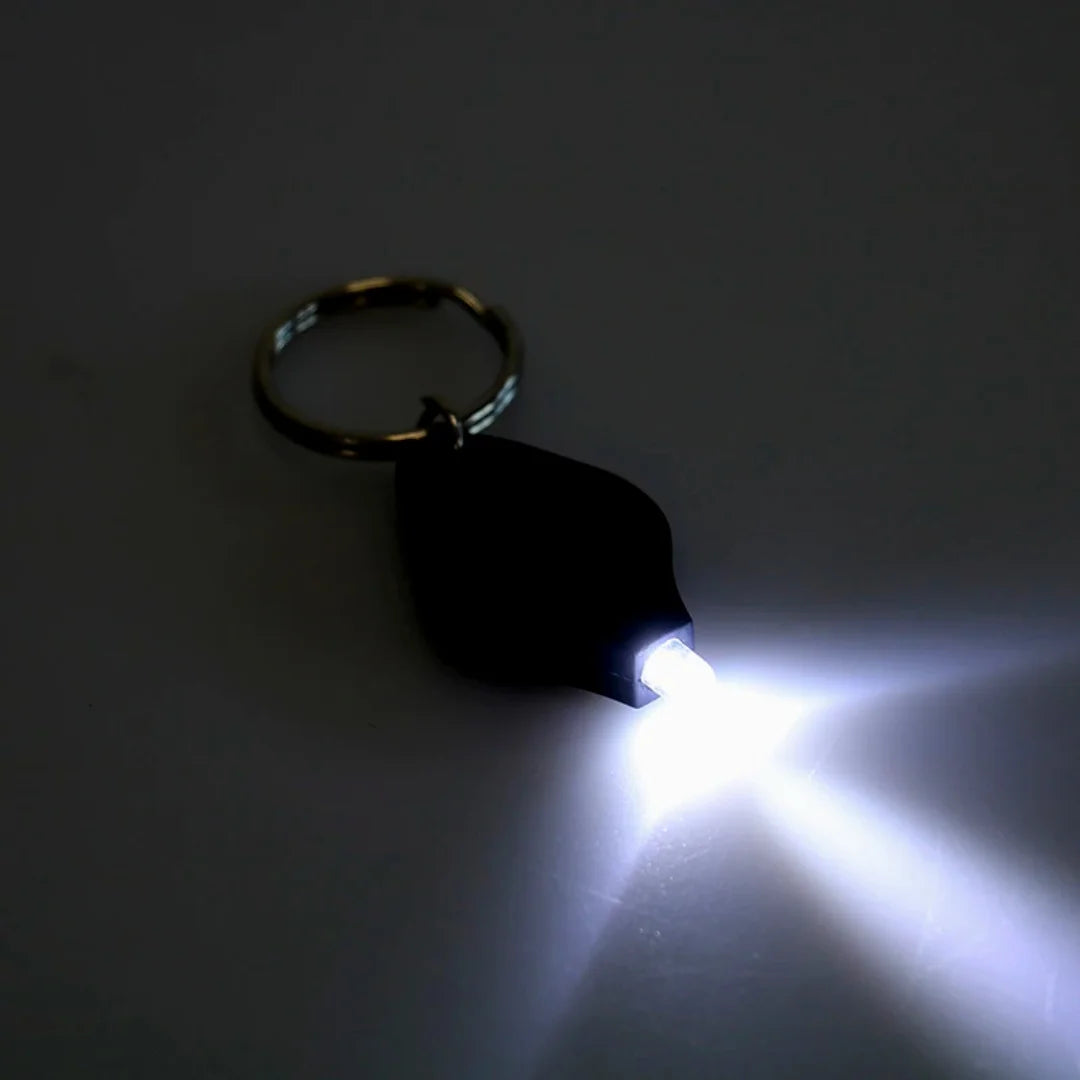AO mini flashlight keychain turned on, emitting bright white light in the dark