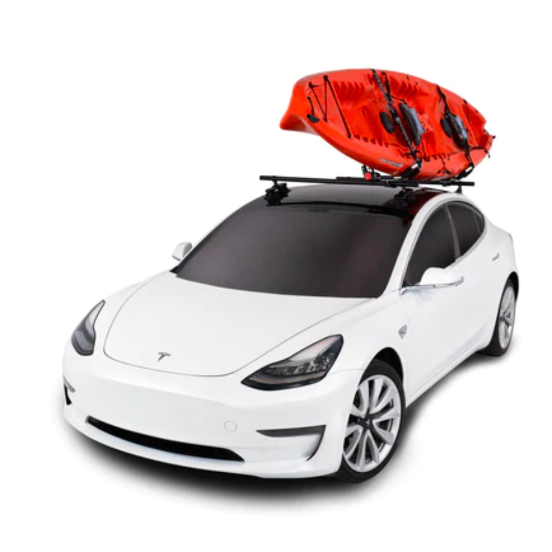 White car with SeaSucker Monkey Bars mounted, carrying a red kayak on the roof.