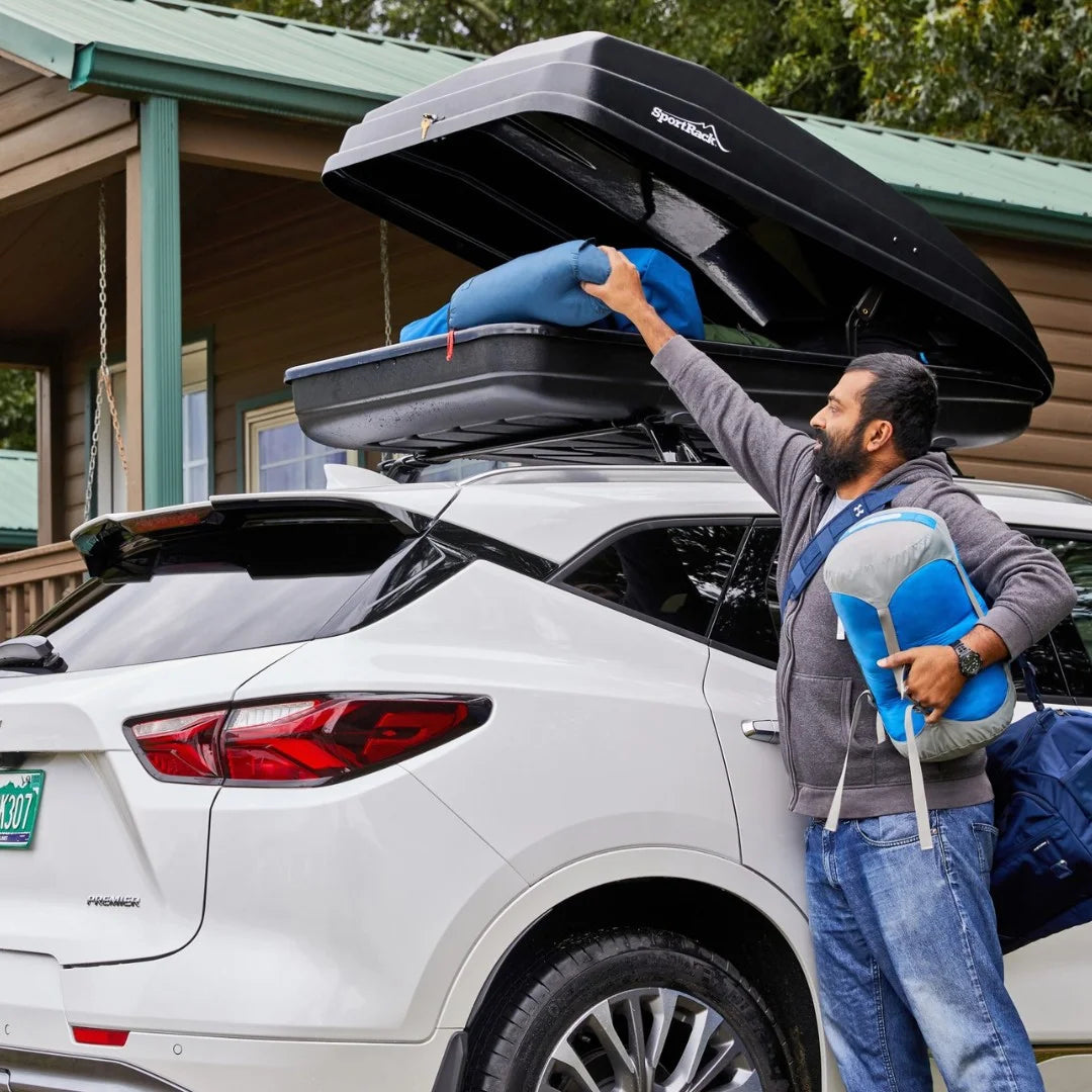 Person reaching into the open Vista XL cargo box on the roof of a white SUV.