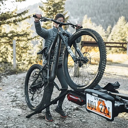 Cyclist lifting e-bike using the Thule ramp on gravel road
