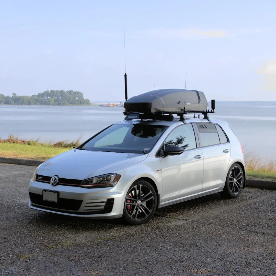 Thule force xt sport roof box mounted on a vw golf vehicle with a body of water background
