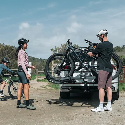 Group of cyclists loading bikes onto Thule OutPace Hitch Bike Rack in outdoor setting