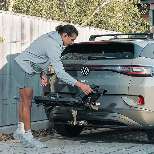 Man loading Thule OutPace Hitch Bike Rack onto Volkswagen ID.4 rear hitch