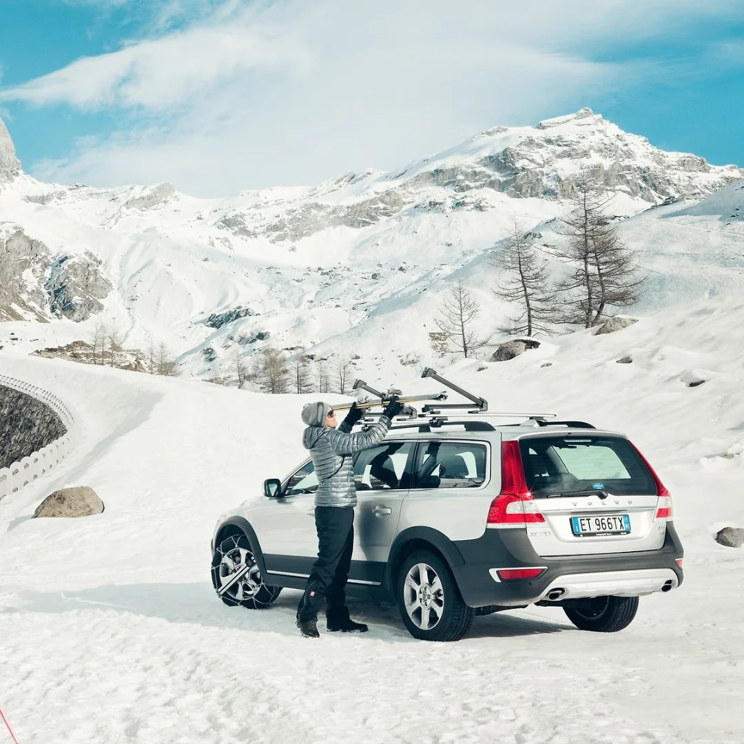 women standing next to a Volvo in the snow and putting her skis into the Thule SnowPack