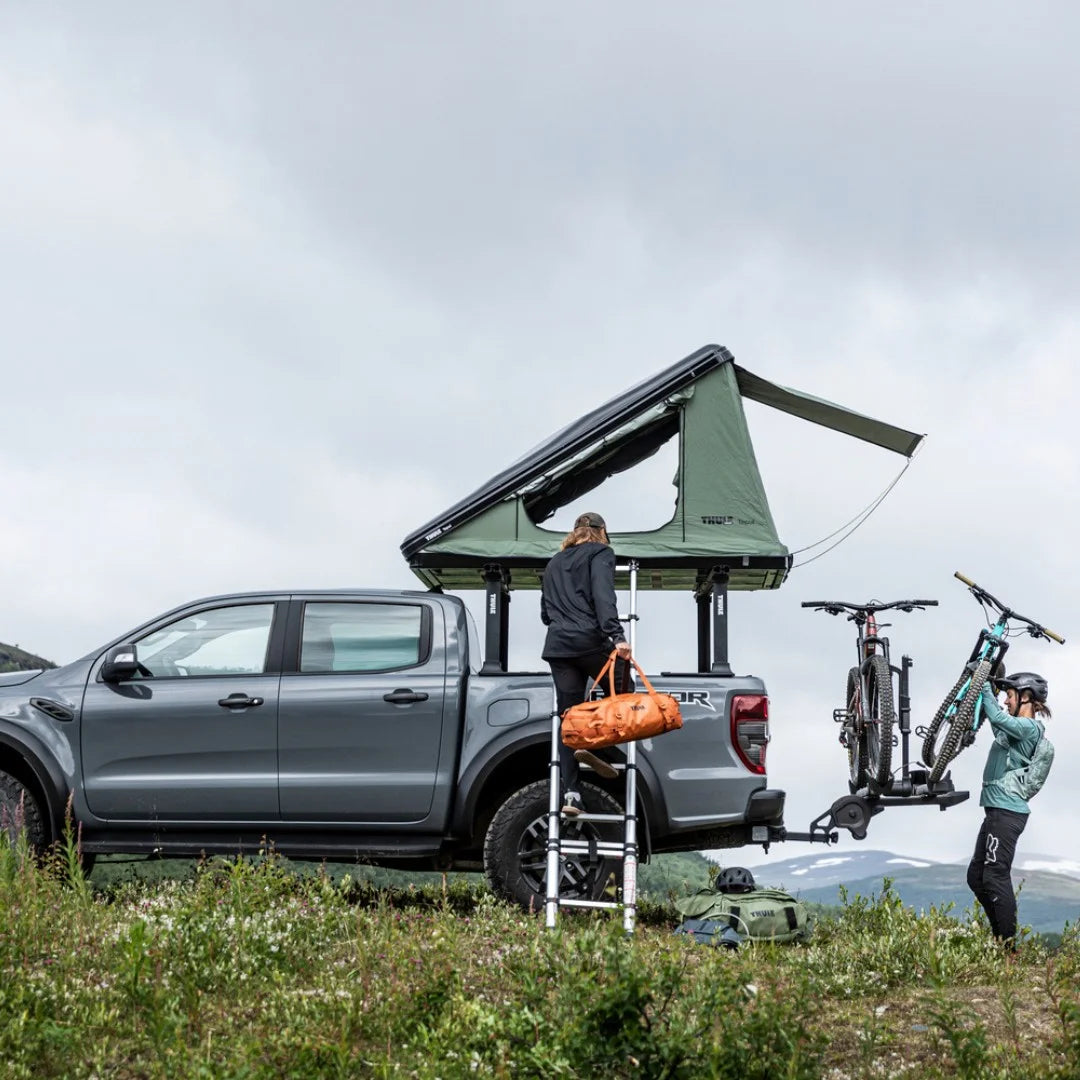 Thule T2 Pro XTR pictured at the back of a car. the car is parked in a beautiful scenery and has a tent on the roof.