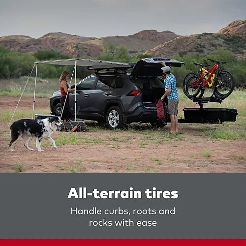 Outdoor family campsite scene with Yakima WarriorWheels cart and all-terrain tires beside SUV – showcases cart use in rugged off-road environment