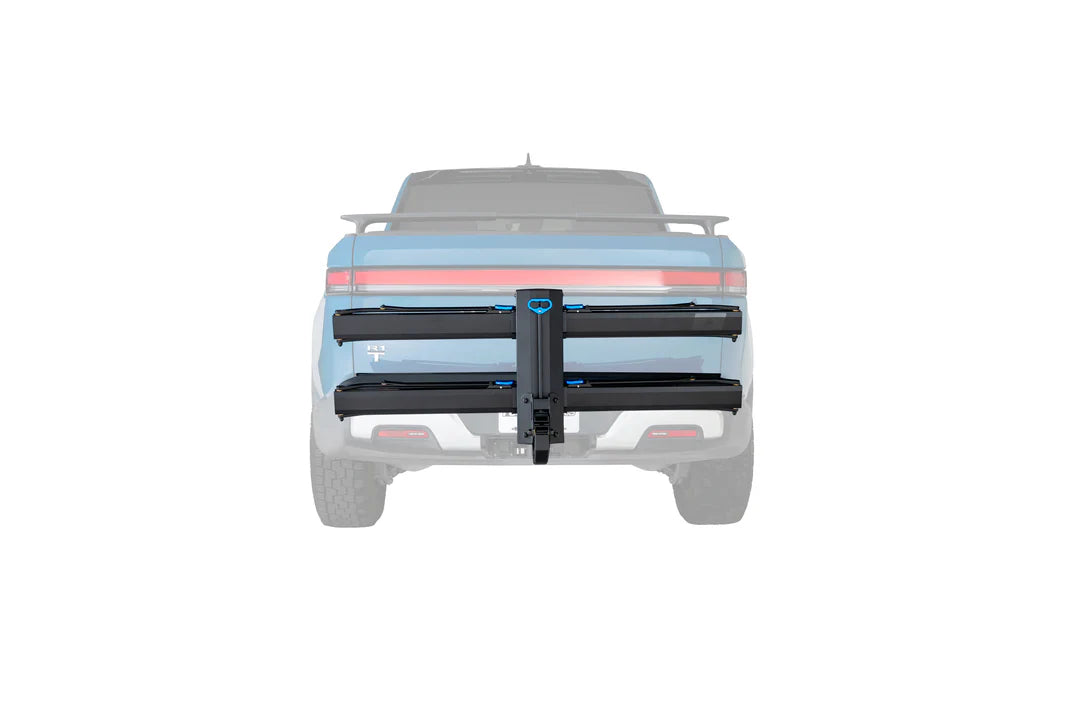 A black dual-bar truck bed rack mounted on the tailgate of a light blue pickup truck, shown from a rear three-quarter view against a solid white background.
