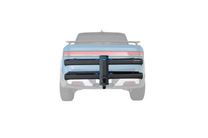 A black dual-bar truck bed rack mounted on the tailgate of a light blue pickup truck, shown from a rear three-quarter view against a solid white background.
