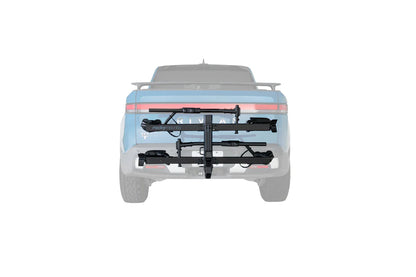A black hitch-mounted bicycle carrier rack attached to the rear of a light blue pickup truck, shown from the back on a plain white background.