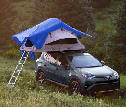 Blue rooftop tent on SUV in wooded outdoor setting