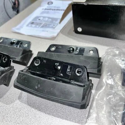 Black electronic components on a gray surface with packaging and instructions in the background.