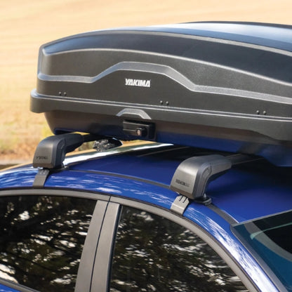 Yakima roof box mounted on a blue car with a blurred natural background