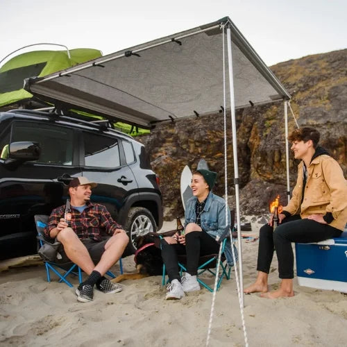 OverNOut roof rack awning creating shaded campsite beside SUV at beach location