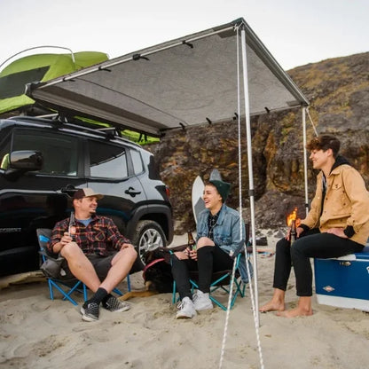 OverNOut roof rack awning creating shaded campsite beside SUV at beach location