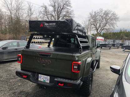 Green Jeep with a roof rack and 'Dog House' brand item in a parking lot.