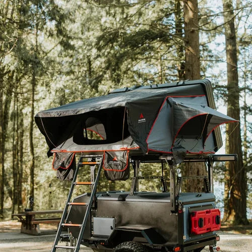 Roof top tent attached to a vehicle in a forest setting