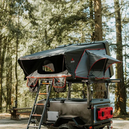 Roof top tent attached to a vehicle in a forest setting