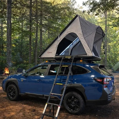 Blue car with a rooftop tent in a forest setting