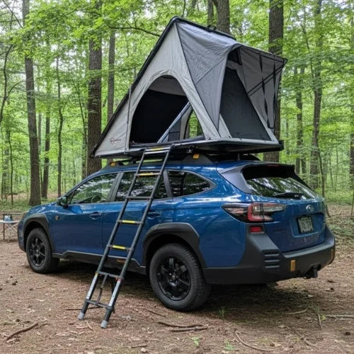 Blue SUV with a rooftop tent in a forest setting