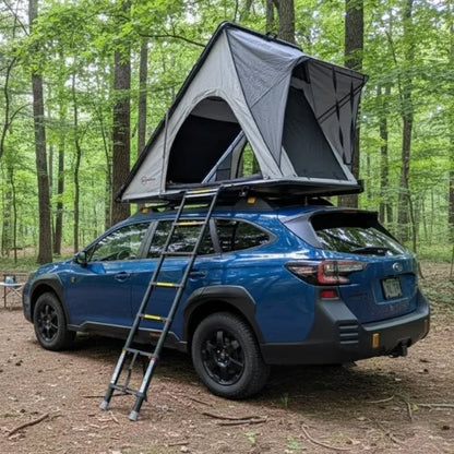 Blue SUV with a rooftop tent in a forest setting