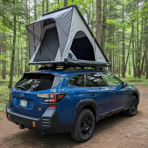 Blue SUV with a rooftop tent and awning in a forest setting