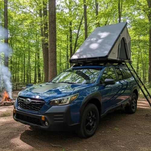 Blue SUV with a rooftop tent parked in a campsite with a bonfire