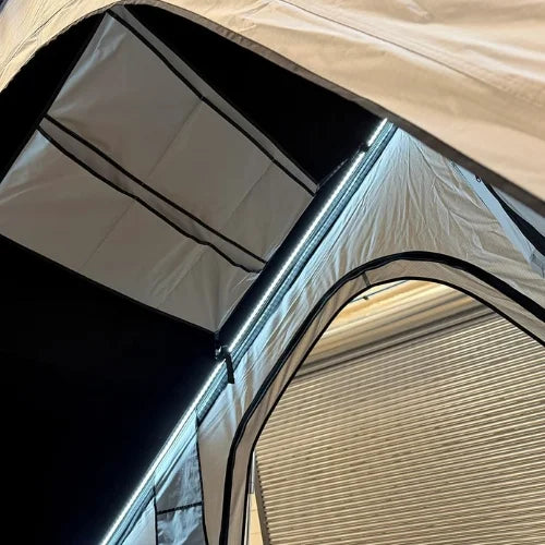 Close-up of a rooftop tent interior with a focus on the fabric, structure, and LED lights