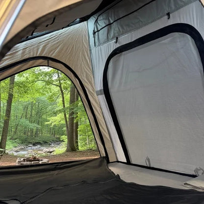Camping rooftop tent with a view of a forest and stream