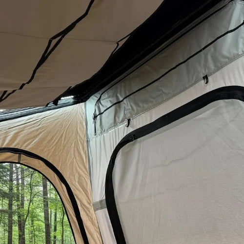 Camping rooftop tent interior with a view of a forest and stream