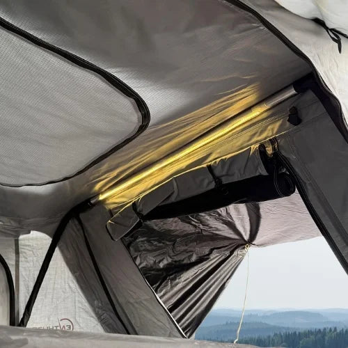 Close-up of a rooftop tent interior with a view of mountains through the window and led light strip
