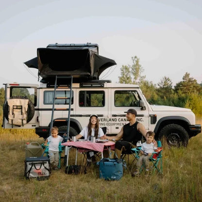 Family camping outdoors with a vehicle equipped for off-road travel and unfolded rooftop tent