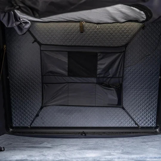 inside of go overland expedition mini rooftop tent featuring Black quilted storage bag with a textured interior on a gray surface highlighting skylight